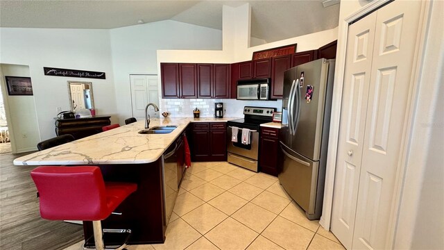 kitchen featuring a breakfast bar, sink, light tile patterned floors, tasteful backsplash, and stainless steel appliances