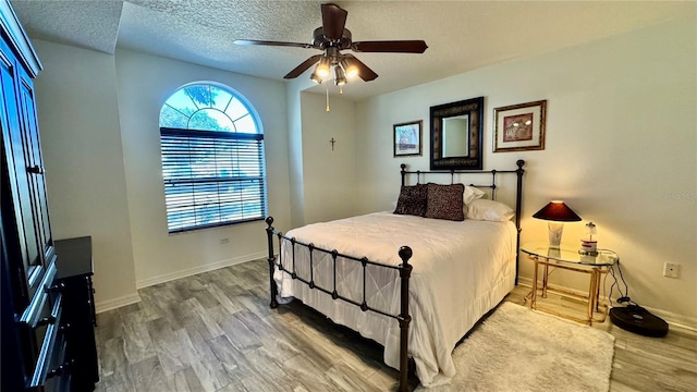 bedroom with wood-type flooring, a textured ceiling, and ceiling fan