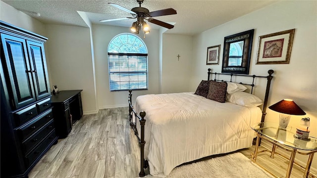 bedroom featuring ceiling fan, light hardwood / wood-style floors, and a textured ceiling