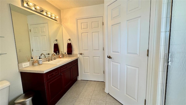 bathroom with tile patterned floors, vanity, a textured ceiling, and toilet