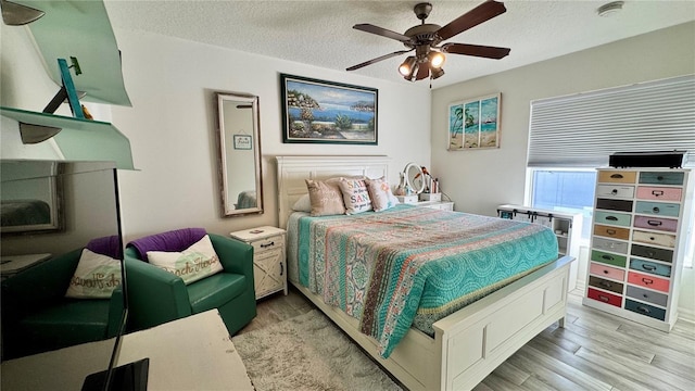 bedroom with ceiling fan, light hardwood / wood-style floors, and a textured ceiling