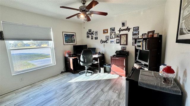 home office with ceiling fan, a textured ceiling, and light wood-type flooring