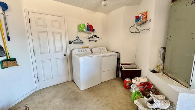 laundry room with light colored carpet, washer and dryer, and a textured ceiling