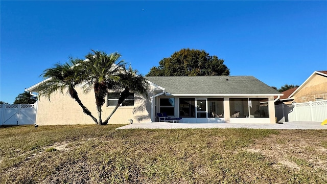 back of property with a sunroom and a lawn