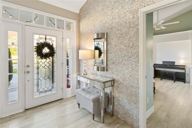 foyer entrance featuring a wealth of natural light, ceiling fan, ornamental molding, and light wood-type flooring