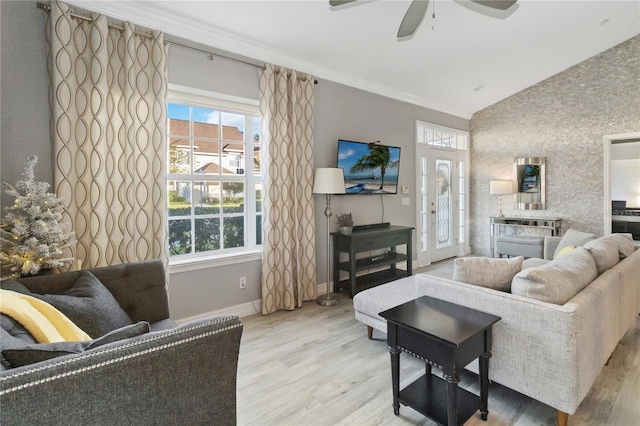 living room featuring ceiling fan, ornamental molding, vaulted ceiling, and light wood-type flooring