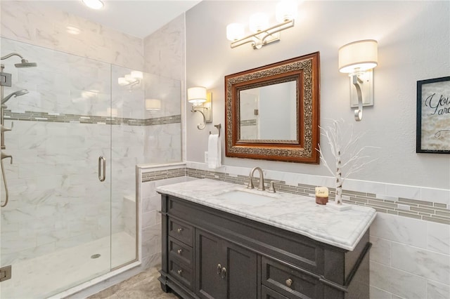 bathroom featuring vanity, a shower with door, and tile walls