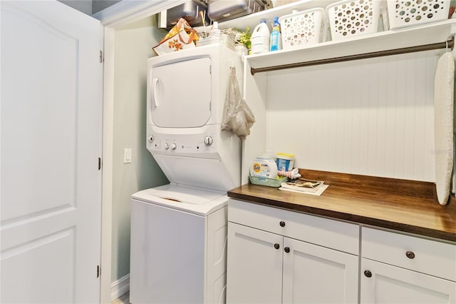 laundry area with stacked washer and dryer and cabinets