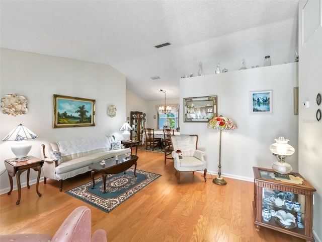 living room with a textured ceiling, a chandelier, vaulted ceiling, and hardwood / wood-style flooring