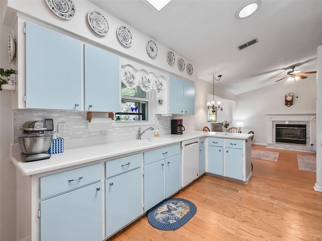 kitchen featuring blue cabinetry, tasteful backsplash, white dishwasher, pendant lighting, and light wood-type flooring