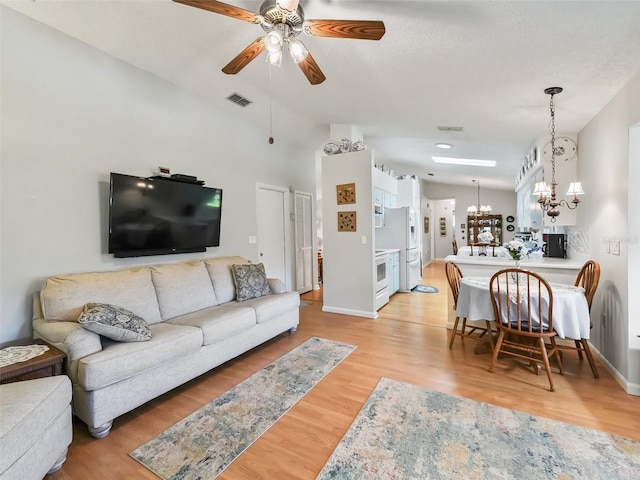 living room featuring light hardwood / wood-style flooring, ceiling fan with notable chandelier, and lofted ceiling