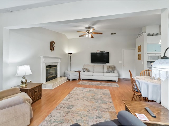 living room with ceiling fan, light hardwood / wood-style floors, and a fireplace