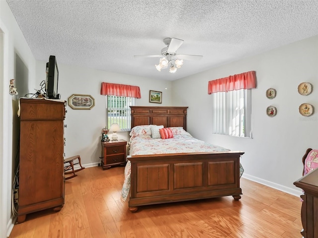 bedroom with a textured ceiling, light hardwood / wood-style floors, and ceiling fan