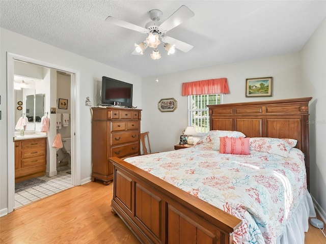 bedroom with a textured ceiling, connected bathroom, light hardwood / wood-style floors, and ceiling fan