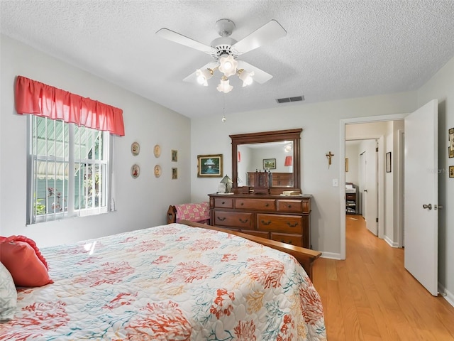 bedroom with a textured ceiling, light hardwood / wood-style flooring, and ceiling fan