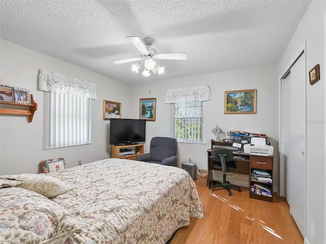 bedroom with ceiling fan, a closet, wood-type flooring, and a textured ceiling