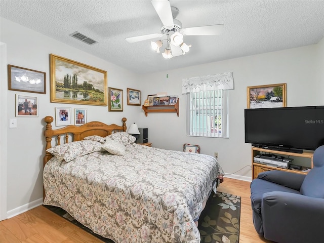 bedroom with ceiling fan, a textured ceiling, and light hardwood / wood-style flooring