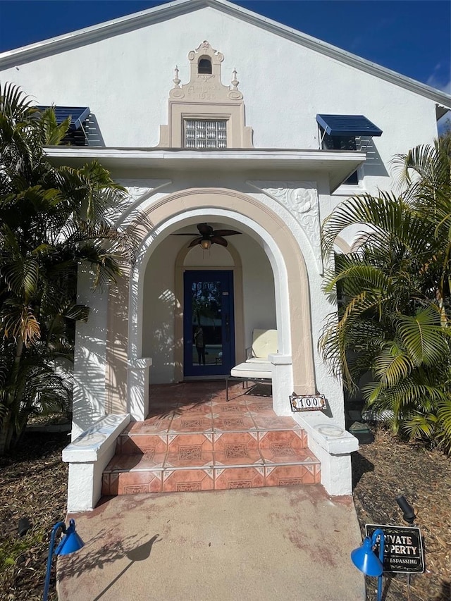 view of exterior entry featuring ceiling fan and a porch