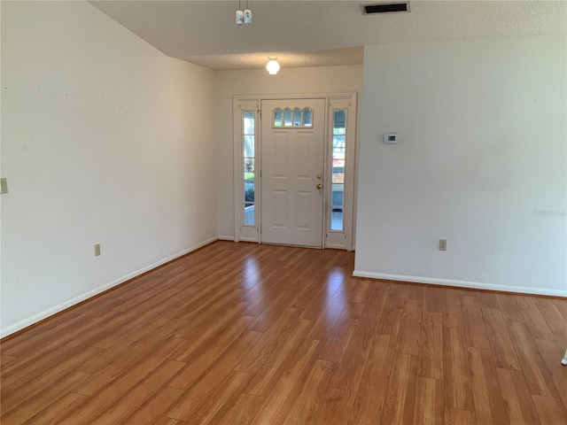 entrance foyer with a textured ceiling and light hardwood / wood-style flooring