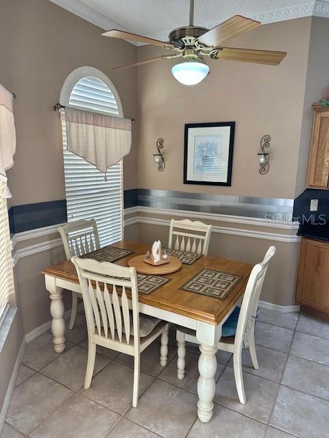 dining space with ceiling fan, light tile patterned floors, and a textured ceiling