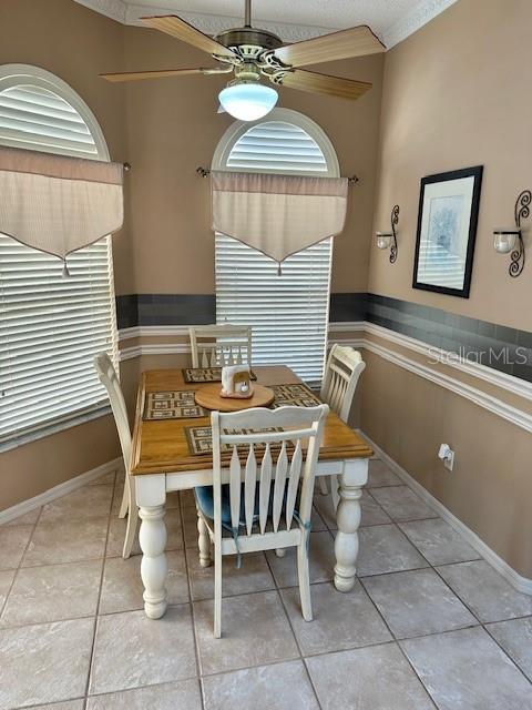 dining space with ceiling fan, light tile patterned flooring, and ornamental molding