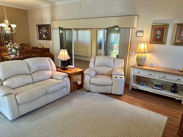 living room featuring crown molding, a notable chandelier, and hardwood / wood-style flooring