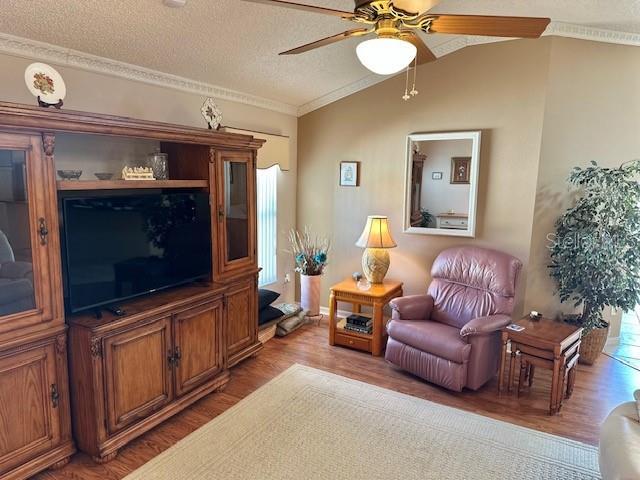 living room featuring ceiling fan, crown molding, hardwood / wood-style floors, a textured ceiling, and vaulted ceiling