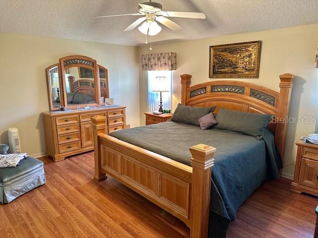 bedroom featuring ceiling fan, light wood-type flooring, and a textured ceiling