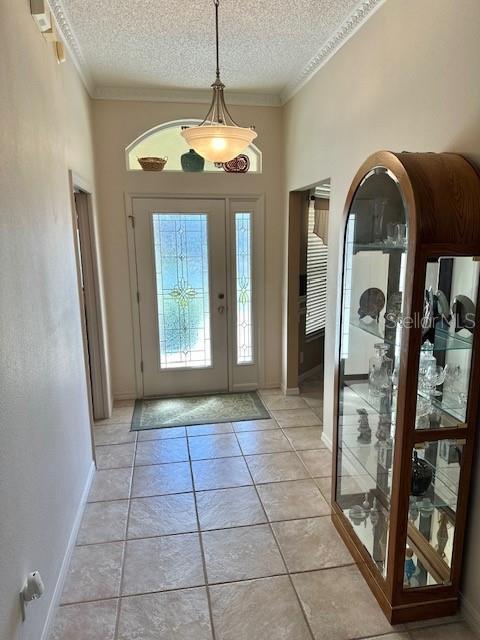 entrance foyer featuring ornamental molding, a textured ceiling, and light tile patterned floors