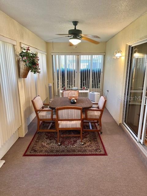 dining space with a textured ceiling, carpet floors, and ceiling fan