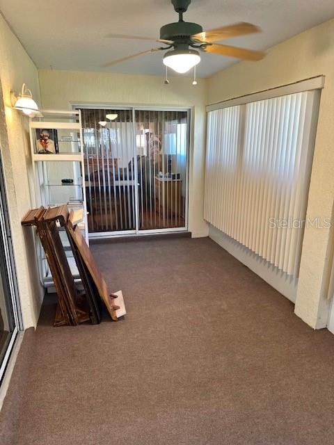 interior space featuring ceiling fan and dark carpet