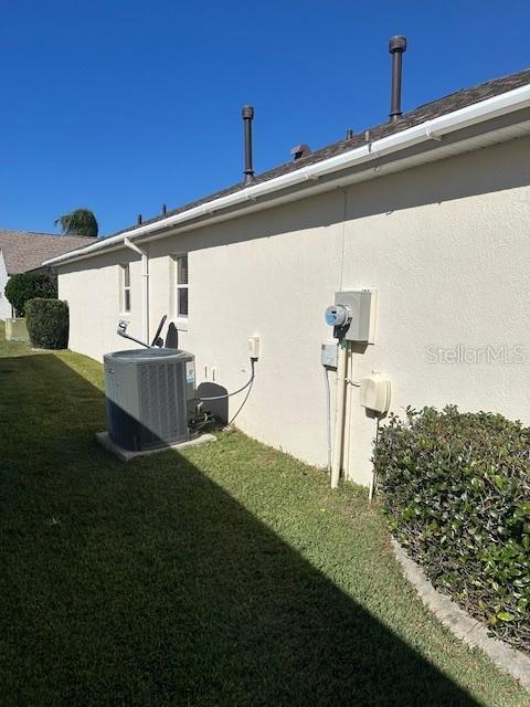 view of side of home featuring a lawn and central AC