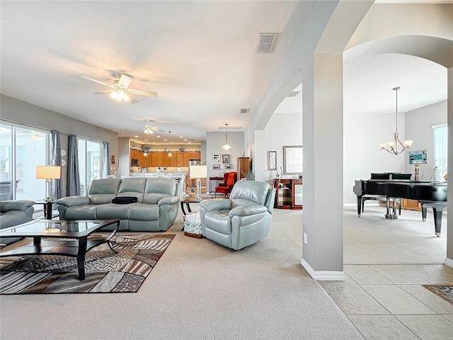 living room featuring light tile patterned floors and ceiling fan with notable chandelier