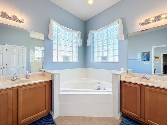 bathroom featuring vanity, a relaxing tiled tub, and tile patterned floors