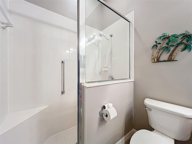 bathroom featuring toilet and a shower with shower door