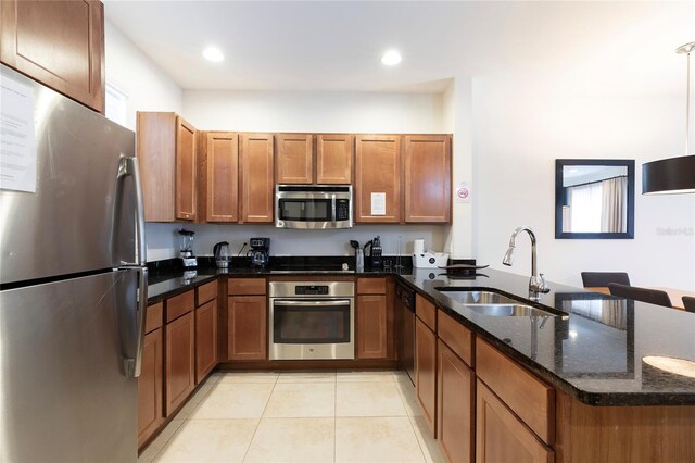 kitchen with dark stone counters, kitchen peninsula, sink, and stainless steel appliances