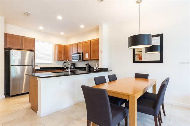 kitchen with kitchen peninsula, stainless steel appliances, sink, pendant lighting, and light tile patterned flooring