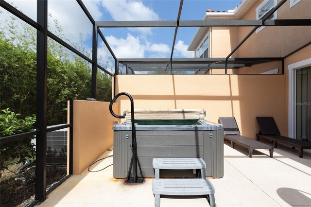 view of patio / terrace featuring a lanai and a hot tub