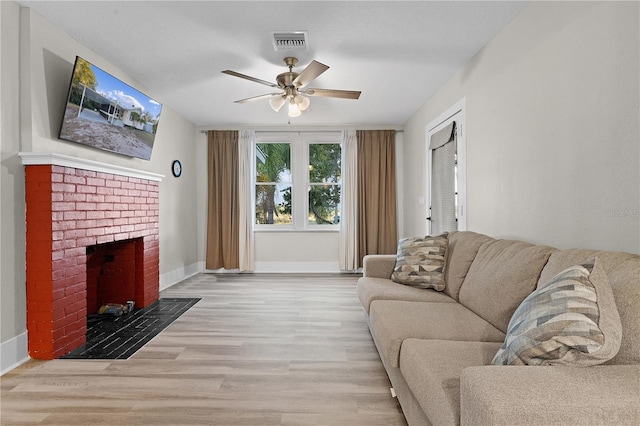 living room featuring a brick fireplace, light hardwood / wood-style flooring, and ceiling fan