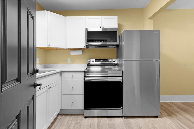 kitchen with white cabinetry, appliances with stainless steel finishes, and light wood-type flooring