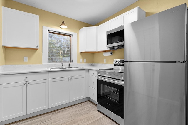 kitchen with white cabinetry, stainless steel appliances, sink, and light hardwood / wood-style flooring