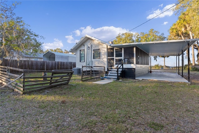 view of front of property with a carport, a sunroom, a front yard, and central air condition unit