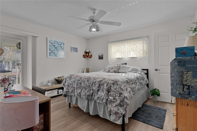 bedroom featuring ceiling fan, light wood-type flooring, and a textured ceiling