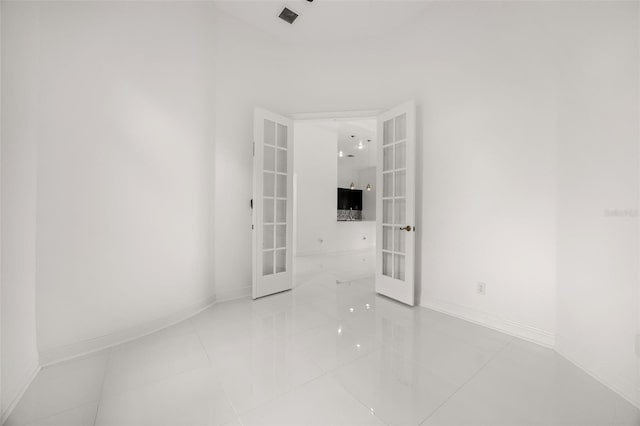 empty room featuring french doors and light tile patterned floors