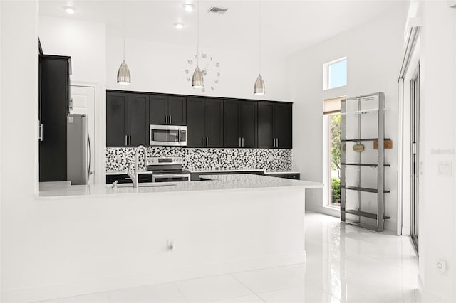 kitchen featuring appliances with stainless steel finishes, sink, hanging light fixtures, and a high ceiling