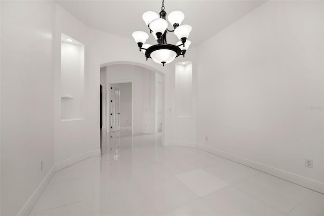 tiled empty room featuring a notable chandelier