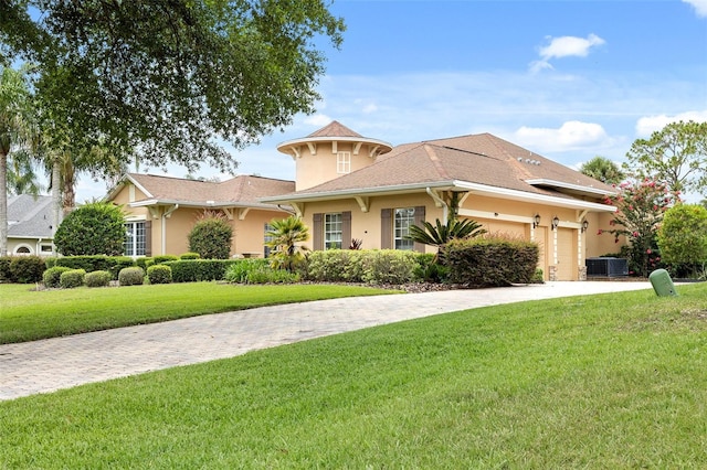 view of front facade with a front lawn, a garage, and central AC