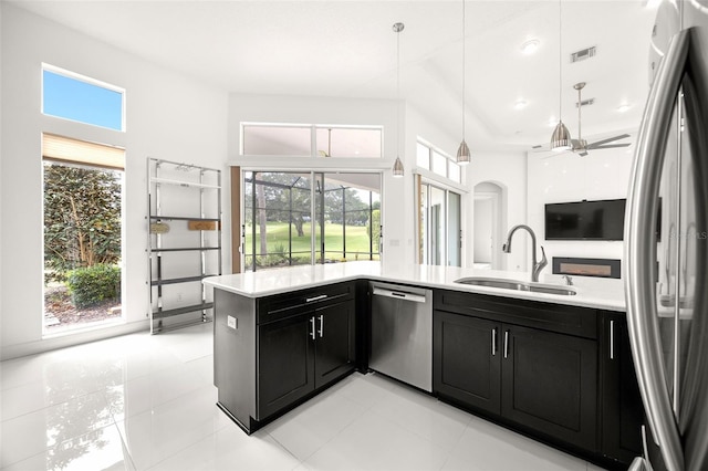 kitchen featuring kitchen peninsula, appliances with stainless steel finishes, ceiling fan, sink, and hanging light fixtures