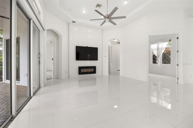 unfurnished living room featuring light tile patterned floors, a large fireplace, and ceiling fan