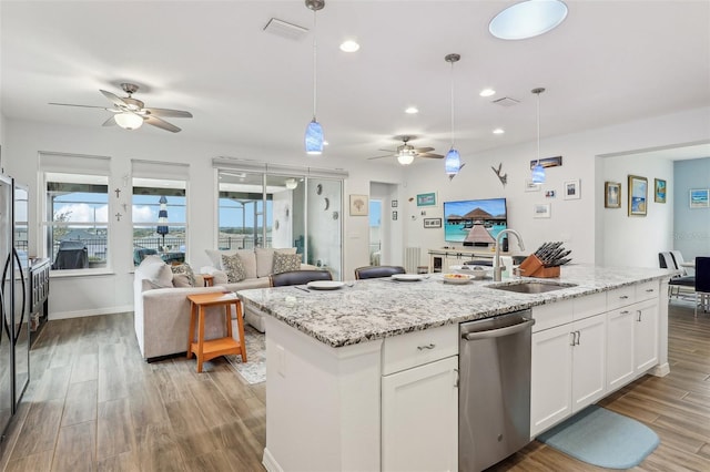 kitchen with stainless steel dishwasher, a kitchen island with sink, sink, white cabinets, and hanging light fixtures